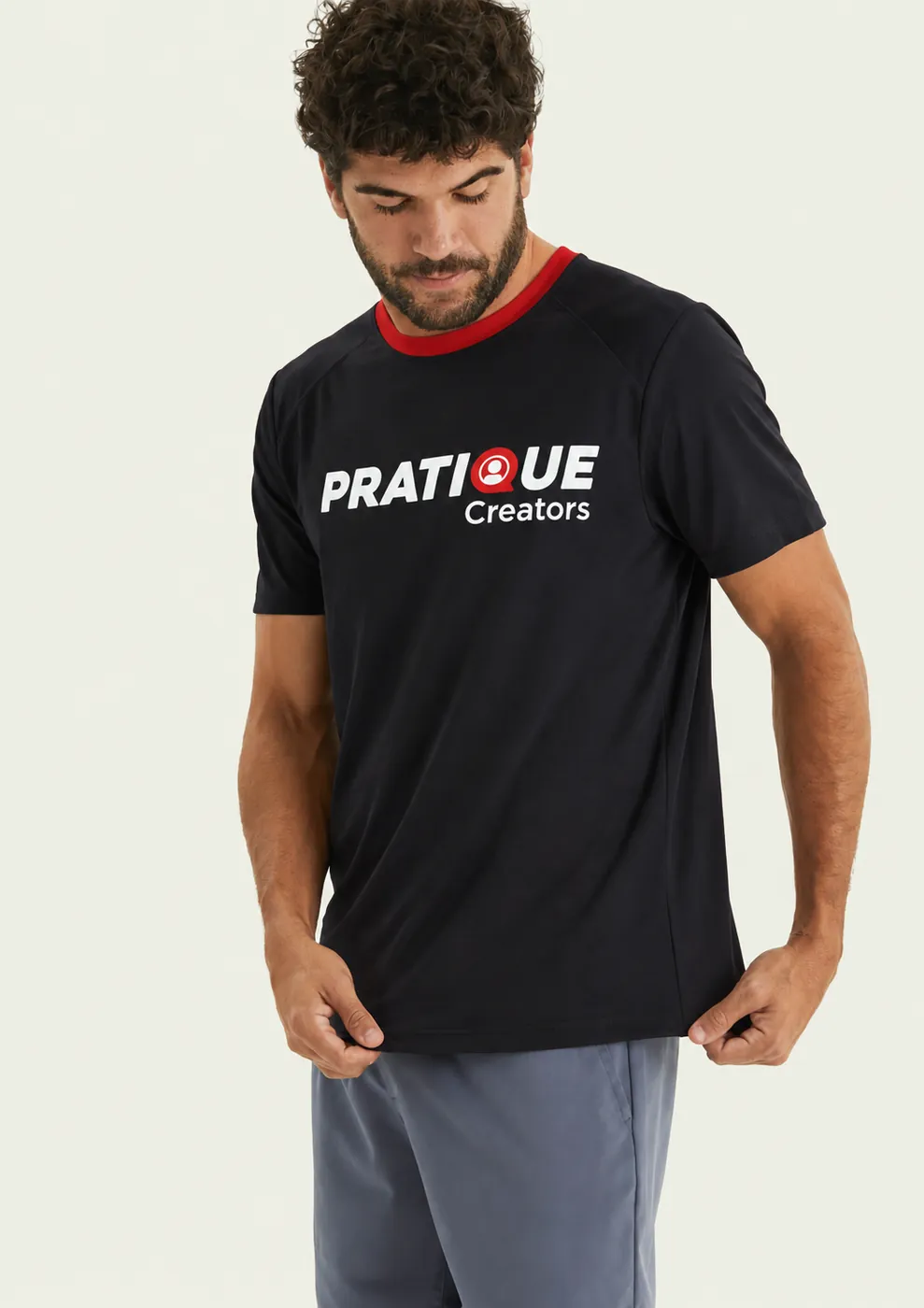 Homem com camiseta esportiva preta personalizada Pratique Creators com gola vermelha contrastante